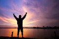 Silhouette of man standing with fists raised up on sunrise background, successful, achievement and winning concept
