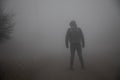 silhouette of a man standing in the foggy road