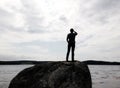 Silhouette of man standing on large rock looking out into a lake Royalty Free Stock Photo