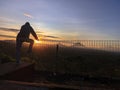 Silhouette of a man standing and holding iron fence against top of mountain view at sunrise. Royalty Free Stock Photo