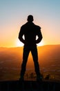 Silhouette of man standing a lone on top of mountain with orange twilight in the dark evening light from the back Royalty Free Stock Photo