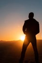 Silhouette of man standing a lone on top of mountain with orange twilight in the dark evening light from the back Royalty Free Stock Photo