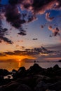 Silhouette man standing on rock at sunset on beach. rocky coast and Beautiful colorful Sunset in atlantic ocean. side view of the Royalty Free Stock Photo