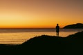 Silhouette of man standing on sand dune overlooking Jimmy\'s Beach at sunrise. Hawks Nest, NSW Australia