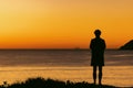 Silhouette of man standing on sand dune overlooking Jimmy\'s Beach at sunrise. Hawks Nest, NSW Australia