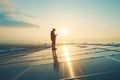 Silhouette of a man standing on solar panels at sunrise with reflections on the surface Royalty Free Stock Photo