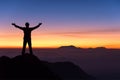 silhouette of man standing and spread hand on the top of mountain to enjoy colourful sky.