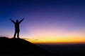 Silhouette of man is standing and spread hand on top of mountain