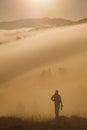 Silhouette man standing. Sunset Over Misty Landscape. Scenic View Of Foggy Morning Sky With Rising Sun Above Misty Forest.