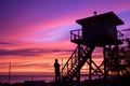 a silhouette of a man standing on top of a lifeguard tower at sunset Royalty Free Stock Photo