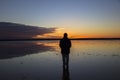 Silhouette of man staring into sunset reflected in shallow lake. Royalty Free Stock Photo