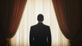 A silhouette of a man in a suit standing in front of large curtains, facing a bright window AI-generated Royalty Free Stock Photo