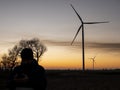 Silhouette of a man at sunset making a photo of wind turbines.wind power plants at sunset Royalty Free Stock Photo