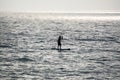 Silhouette of a man on a surfer in the middle of the sea, against the sun. Art photo, black and white, monochrome