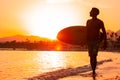 Silhouette man surfer in sunset light walking down beach with surfboard near waters edge enjoying summer time practice Royalty Free Stock Photo