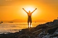 Silhouette of man with their hands in the sunset on the sea. The concept of free life and relaxation. Royalty Free Stock Photo