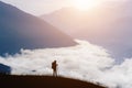 Silhouette of a person traveler in the mountains early in the morning at sunrise. The valley is filled with clouds