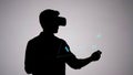 Silhouette Man in VR Headset Using Holographic Menu wearing interacting with floating image represents Royalty Free Stock Photo