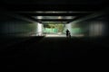 Silhouette of man walking with bike on upslope in road tunnel wi