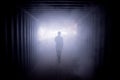 Silhouette of a man walking in a dark tunnel to the light Royalty Free Stock Photo