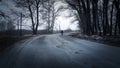 Silhouette of a man walking in the distance on a forest road in winter. There is a lot of snow. A lonely boy walks along a path in Royalty Free Stock Photo