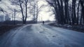 Silhouette of a man walking in the distance on a forest road in winter. There is a lot of snow. A lonely boy walks along a path in Royalty Free Stock Photo