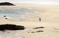 Silhouette of a man walking in the immense beach of Newquay, a popular destination for surfers.