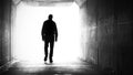 A silhouette of a man walking out of a dark tunnel towards the light Royalty Free Stock Photo