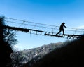 Silhouette of man walking over a suspension old bridge blue sky background Royalty Free Stock Photo