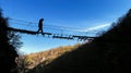 Silhouette of man walking over a suspension old bridge blue sky background Royalty Free Stock Photo