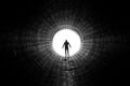 Silhouette of a man walking to the light at the end of a big tunnel. Concept of escape, exit, freedom, clinical death Royalty Free Stock Photo