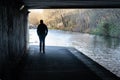 Silhouette of a Man Walking Under a Viaduct Near a Canal.