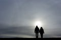 Man and woman holding hands and walking together towards rising sun Royalty Free Stock Photo