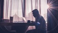 Silhouette of man at work using laptop against window background illuminated by natural sun glare Royalty Free Stock Photo