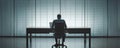 Silhouette of man working at desk with laptop in a dark office, blinds casting shadows in background Royalty Free Stock Photo