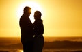 Silhouette of mature couple bonding on holiday. Senior couple being close at sunset on the beach. Married couple being