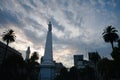 Silhouette of May Pyramid and palm trees against sunset sky on Plaza de Mayo in Buenos Aires