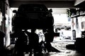 Silhouette of mechanics servicing cars at a small workshop