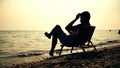 Silhouette men in chair reading book on the beach sunset Royalty Free Stock Photo