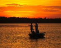 Silhouette of men fishing in a boat on lake after sunset