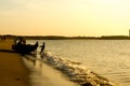 Silhouette of men pushing a tourist fishing boat into the ocean at a Gujarat beach