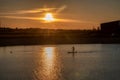 Silhouette of men on sup board with oar in hands on lake in evening with magnificent sunset in background Royalty Free Stock Photo