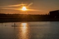 Silhouette of men on sup board with oar in hands on lake in evening with magnificent sunset in background Royalty Free Stock Photo