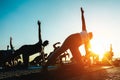 Silhouette of men and women doing yoga outdoor - Group of people doing meditation at sunset - Spiritual concept for healthy and