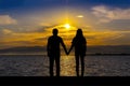 Silhouette of men and women who hold hands, on the seaside at sunset