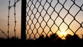 Silhouette of mesh fence and barbed wire with dark sky at sunset Royalty Free Stock Photo