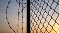 Silhouette of mesh fence and barbed wire with dark sky at sunset Royalty Free Stock Photo