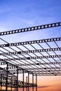 Silhouette of metal castellated beam of factory building structure in construction site against sunset sky background