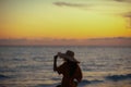 Modern woman on seashore at sunset adjusting straw hat Royalty Free Stock Photo