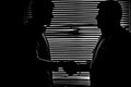 Silhouette in monochrome of two men shaking hands darkness Royalty Free Stock Photo